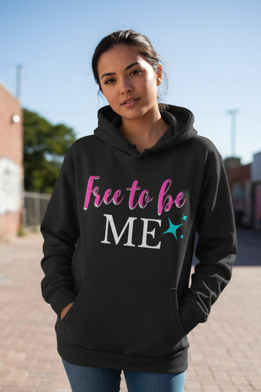 A dark charcoal gray pullover hoodie with a front kangaroo pocket and drawstring hood, featuring the text 'Free to be ME' in pink, white, and teal on the chest, displayed on a clean white background.